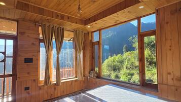 Quarto de cabana de madeira com uma cama grande, paredes de madeira e vista para as montanhas.