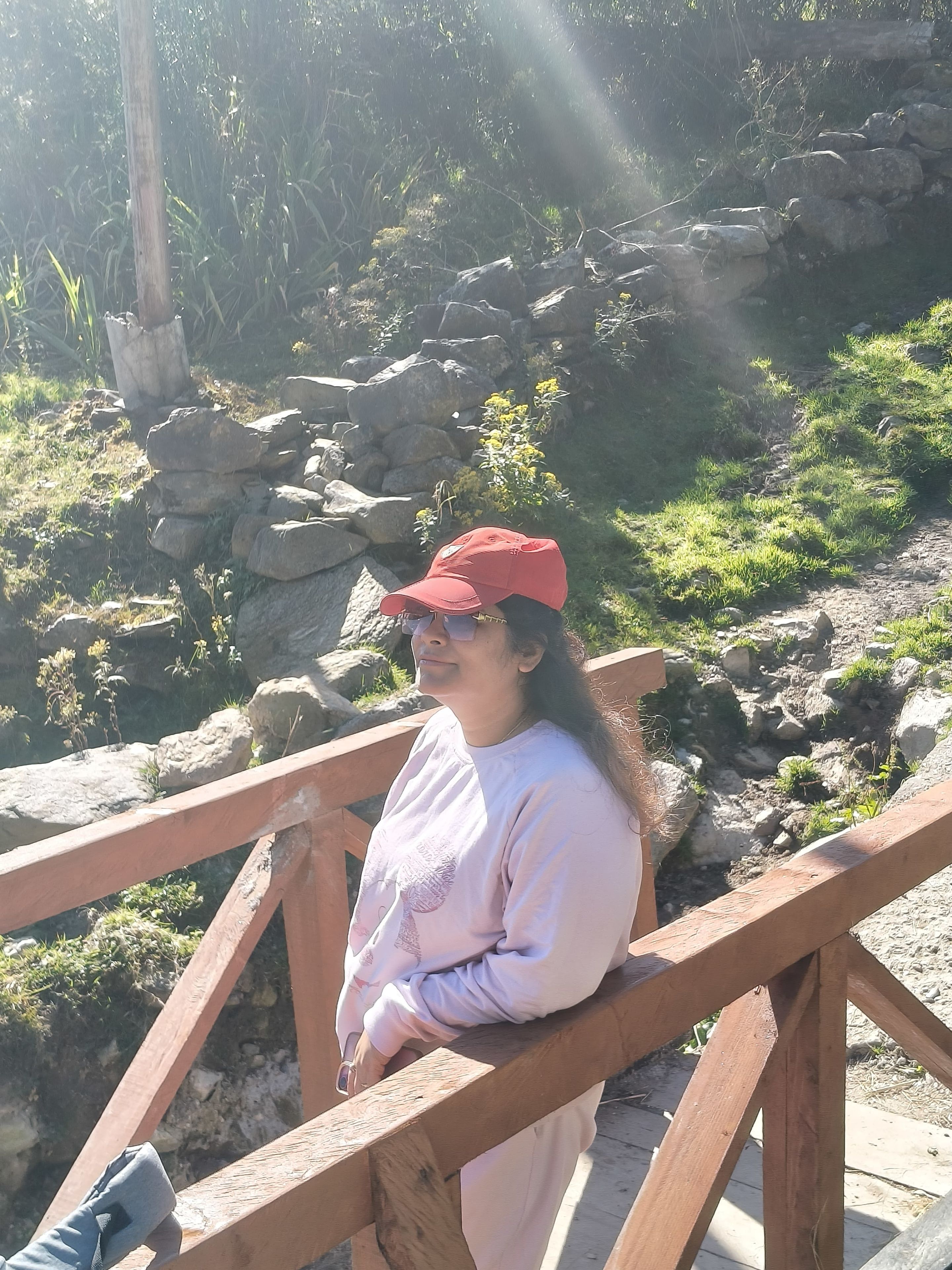 Una persona de pie sobre un puente de madera, con un paisaje rocoso al fondo.