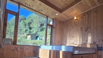 Ein Zimmer mit einem großen Fenster, einer Holzbalkendecke und einem gemusterten Teppich.