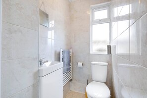 Een moderne badkamer met een wit toilet, een wastafel en een spiegel.