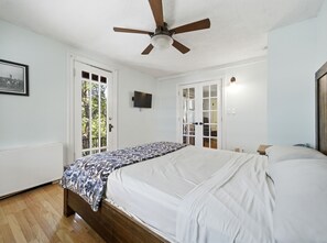 A bedroom with a bed, a ceiling fan, a television, and a door leading to a balcony. - Delightful 1-bedroom condo in vibrant Denver perfect for your stay (Denver)