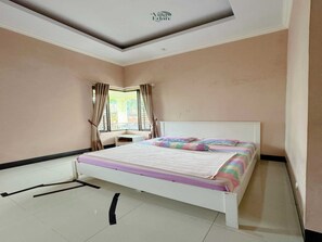A bedroom with a bed, a window with curtains, and a ceiling with a recessed design.