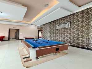 A pool table in a room with patterned wallpaper and a ceiling with recessed lighting. - Cozzy Villa HN (Cisarua)
