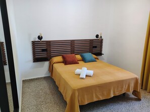 Een keurig opgemaakt bed met hoofdbord, twee handdoeken en twee kussens.