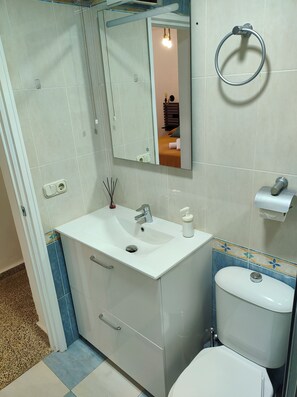 A bathroom with a white sink, mirror, toilet, and a towel ring. - Jédula Apartment (Jédula)