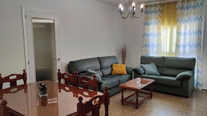 A living room with a dining table, two sofas, a chandelier, and a door with a window. - Jédula Apartment (Jédula)