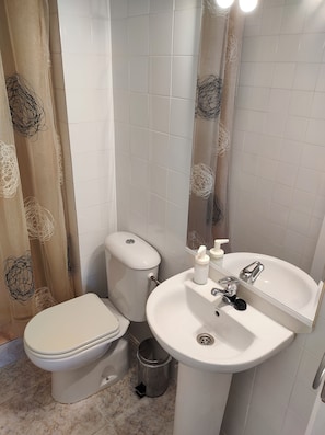 A bathroom with a toilet, sink, and shower curtain. - Jédula Apartment (Jédula)