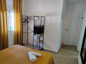 A hotel room with a bed, a wardrobe with shelves, a door, and a window with curtains. - Jédula Apartment (Jédula)
