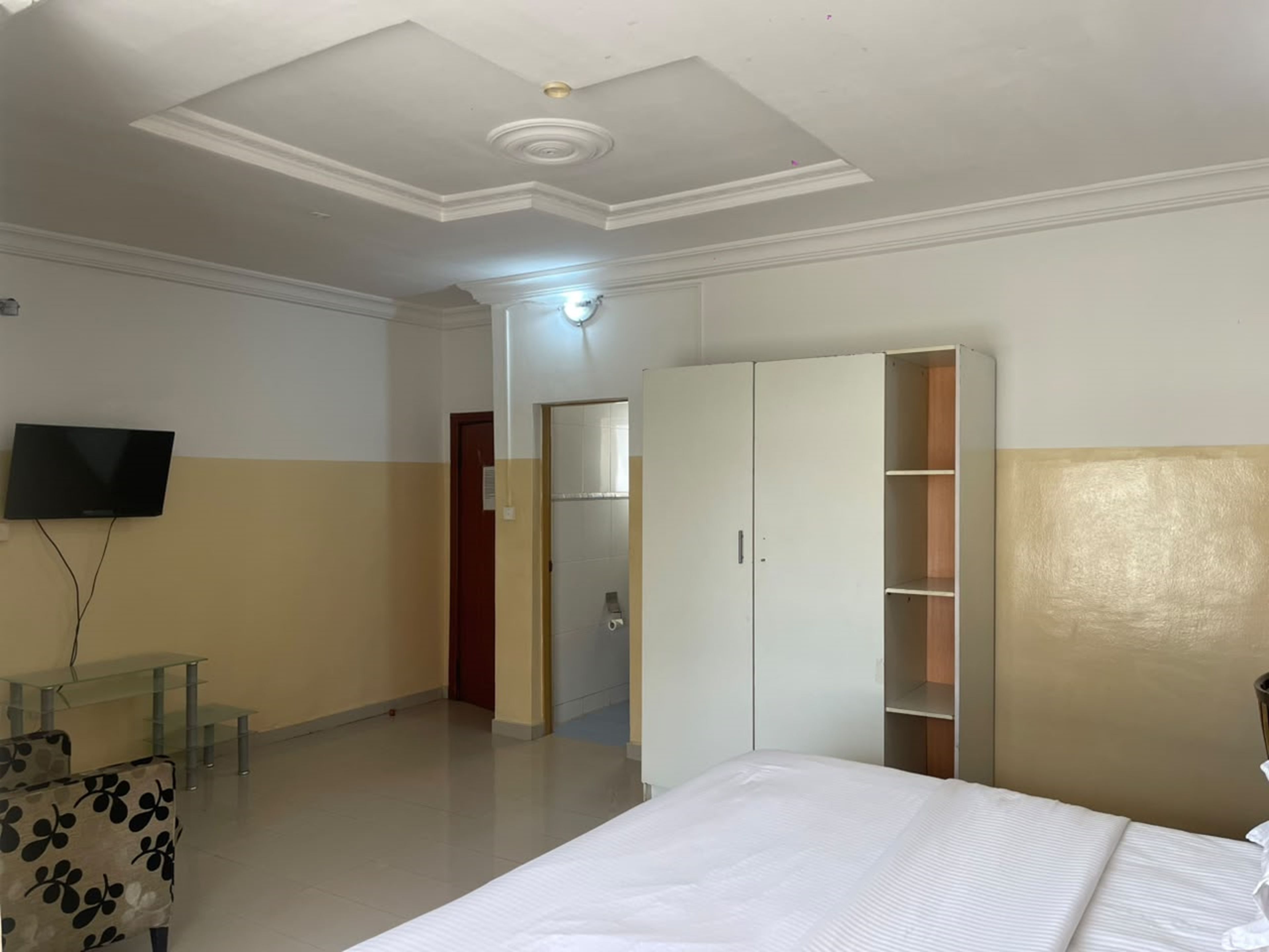 A hotel room with a bed, wardrobe, television, and a small table.