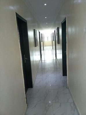 A corridor with doors on both sides, leading to a bright room at the end. - Villa Angelia Hotel Ikoyi Annex 2 (Lagos)