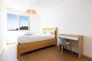 A bedroom with a bed, a desk, and a chair. - Modern Seaview Apt with pool, 15 min Walk to Beach (Câmara de Lobos)