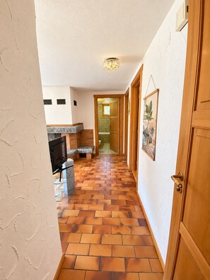 A hallway with a tiled floor, a wooden door, and a framed picture on the wall. - Brienz Mountain Base – Simple & Comfortable (Brienz/Brinzauls)