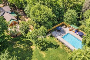 Ein Wohnhaus mit Swimmingpool, Terrassenmöbeln und einem eingezäunten Garten.