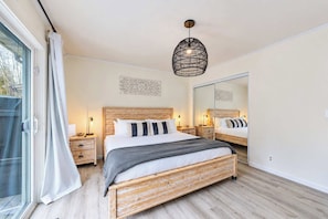 Ein Schlafzimmer mit einem großen Bett, Nachttischen, einer Pendelleuchte und einer Schiebetür.