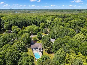 A residential property with a swimming pool, surrounded by dense forest. - Blue Haven Retreat | Pool • Theater • Arcade Room! (Fennville)