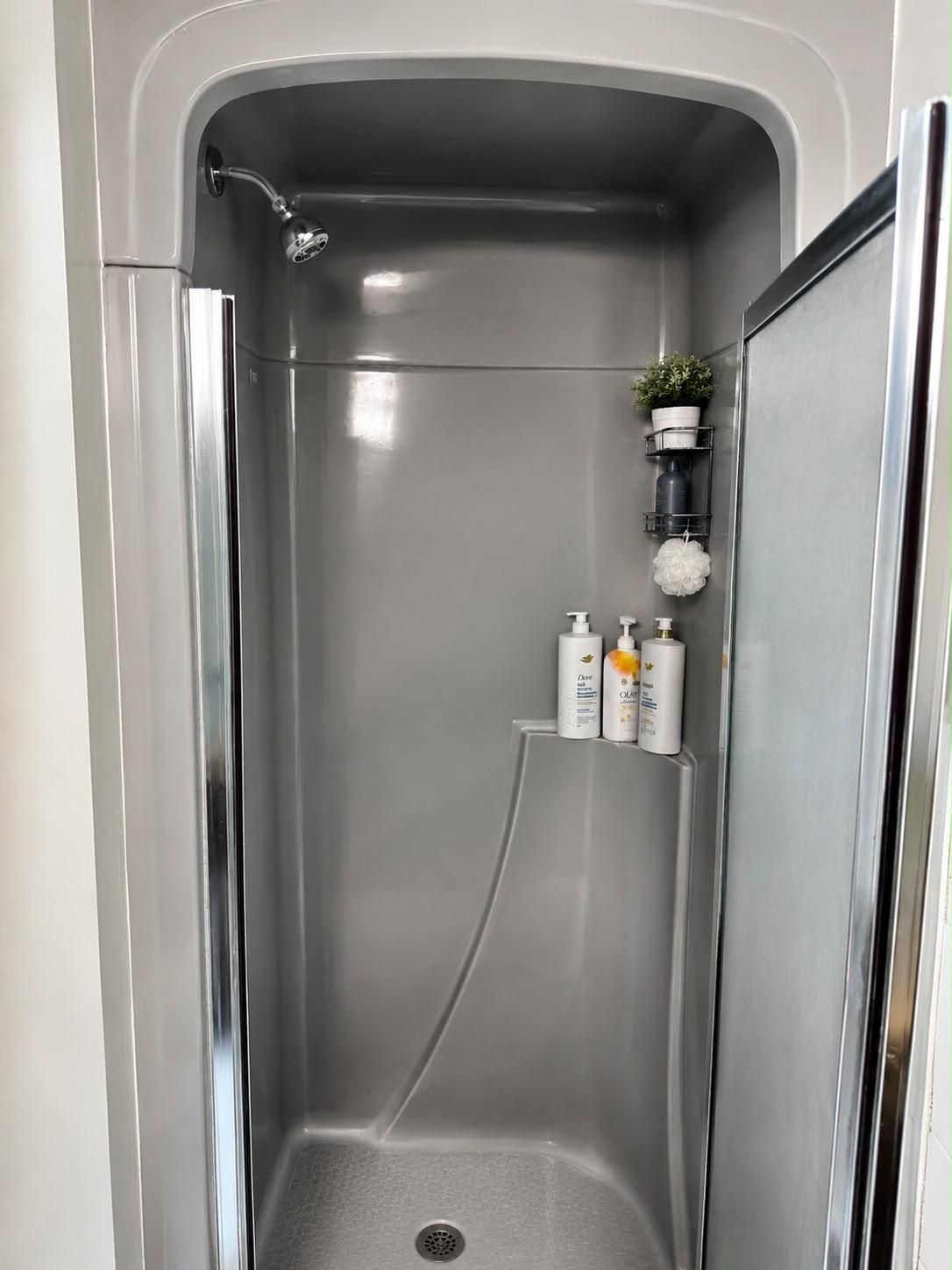 A modern shower enclosure with a built-in shelf holding toiletries.