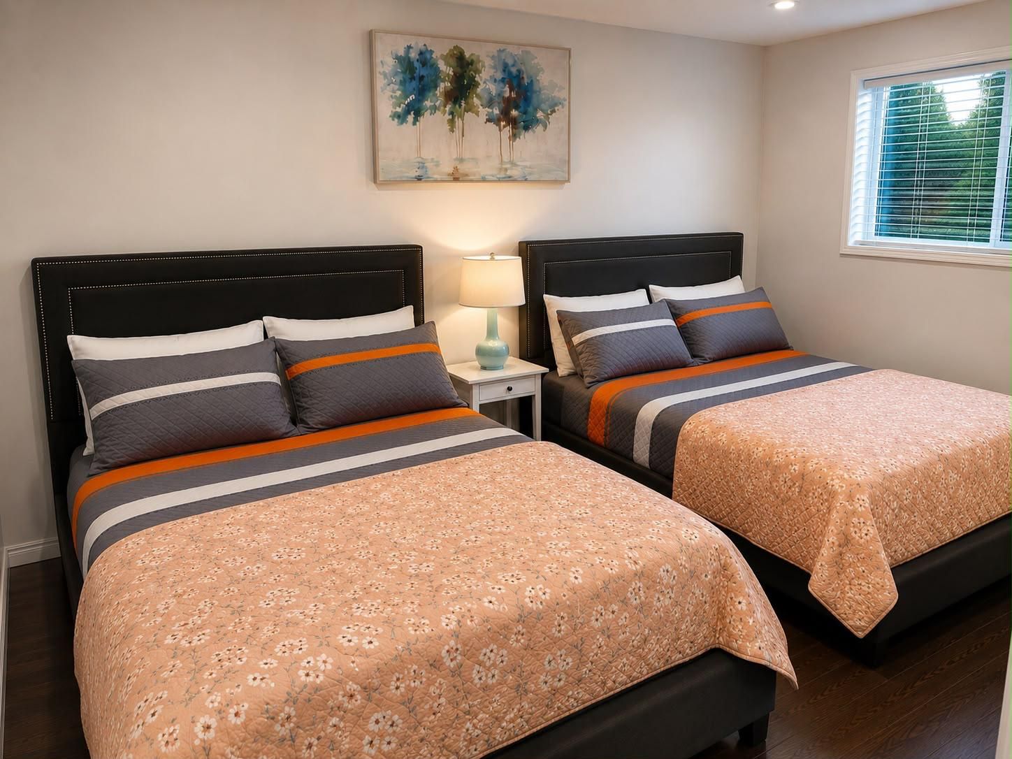 Un dormitorio con dos camas, una mesita de noche, una lámpara y un cuadro en la pared.