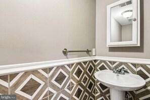 Une salle de bain avec un lavabo blanc, un porte-serviettes et un miroir.