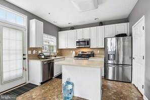 A modern kitchen with white cabinets, stainless steel appliances, and a large water dispenser. - jjjjjjjjjjj (Hanover)