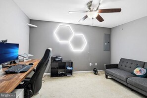 Une chambre moderne équipée d’un bureau, d’un ordinateur, d’une chaise et d’un canapé gris.