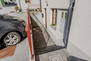 Un coche aparcado en una entrada con una rampa roja que lleva a la puerta de un edificio.