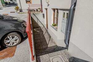 Un coche aparcado en una entrada con una rampa roja que lleva a la puerta de un edificio.