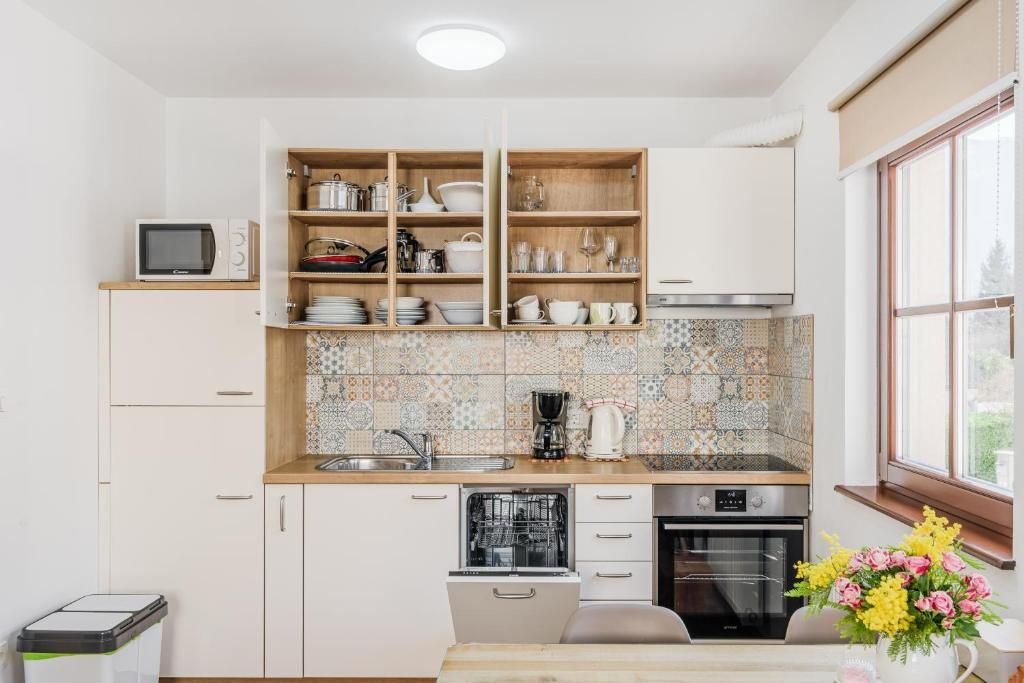 Una cocina con armarios blancos, lavavajillas, horno y microondas.