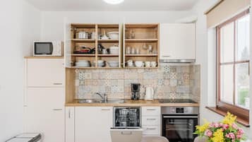 Una cocina con armarios blancos, lavavajillas, horno y microondas.
