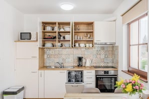 Una cocina con armarios blancos, lavavajillas, horno y microondas.