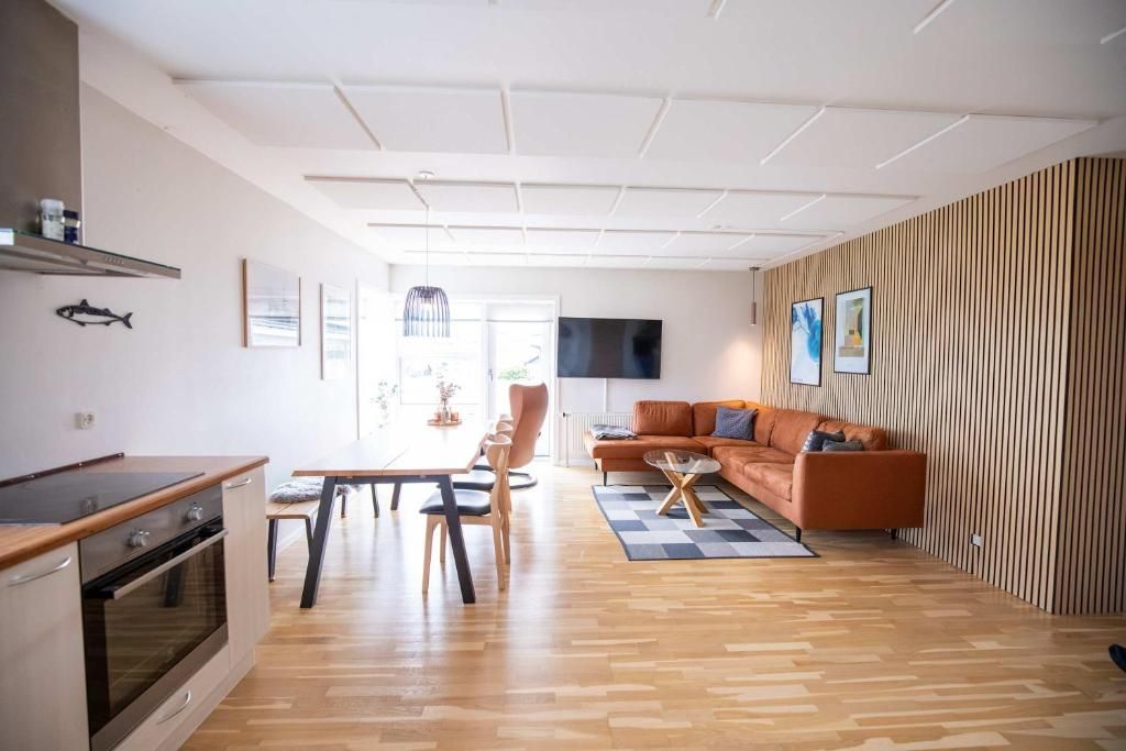 Un espacio habitable moderno con cocina, comedor y zona de estar con sofá y televisor.