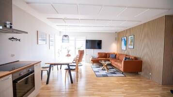 Un espacio habitable moderno con cocina, comedor y zona de estar con sofá y televisor.