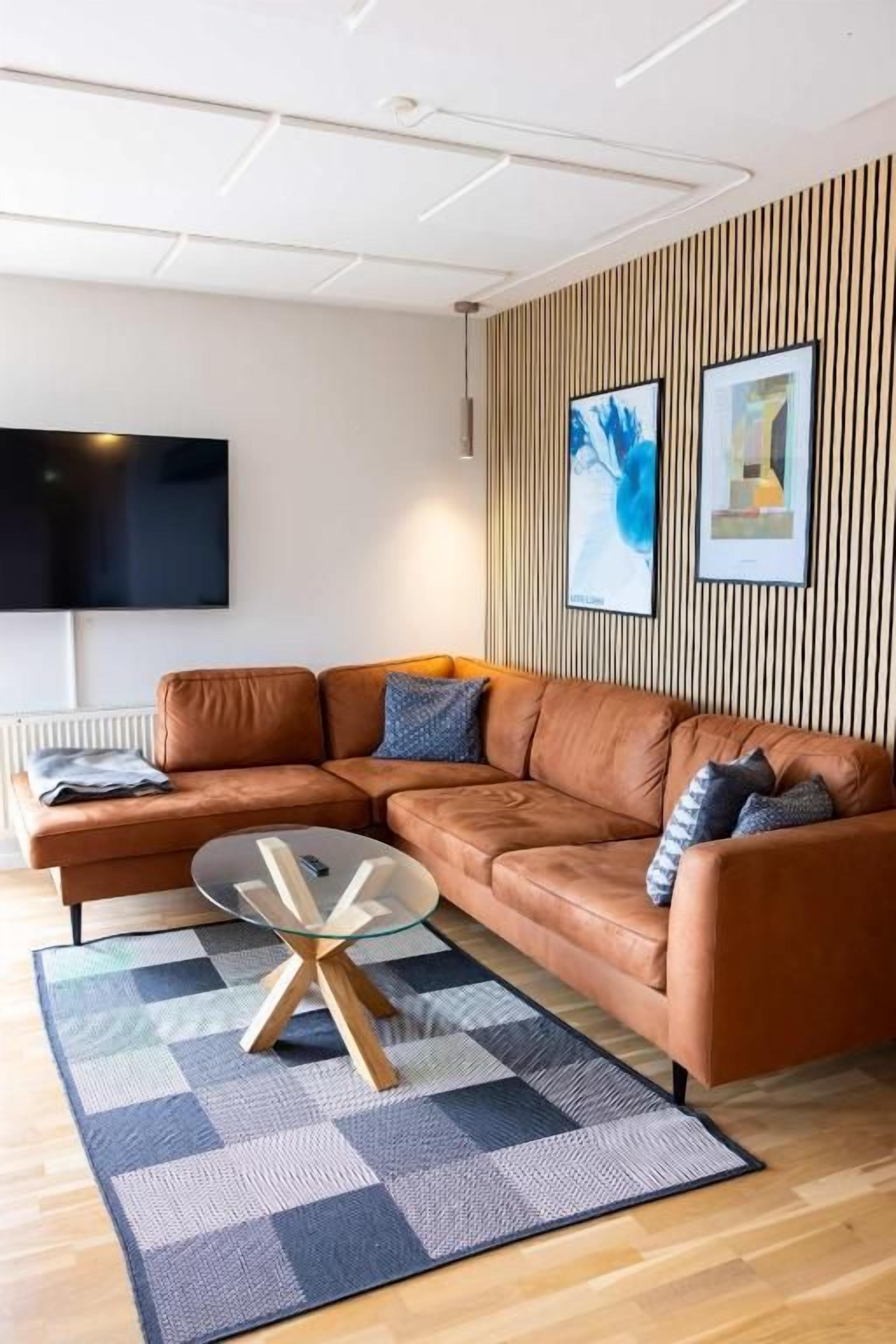 A modern living room with a sectional sofa, a glass coffee table, and a patterned rug.
