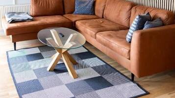 A modern living room with a sectional sofa, a glass coffee table, and a patterned rug.