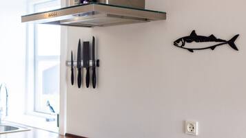 A kitchen with a stainless steel range hood, a wooden countertop, and a wall-mounted fish decoration.
