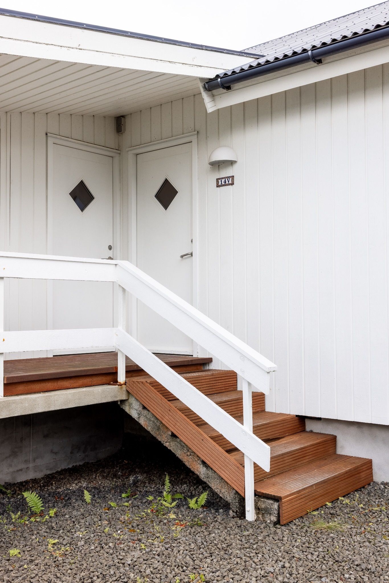 Un edificio blanco con una escalera que lleva a una puerta con la inscripción '14V'.
