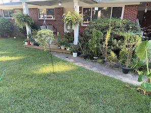A well-maintained garden with various potted plants and a lawn in front of a brick house. - Superb 3-bedroom house with AC in vibrant Atlanta (Atlanta)