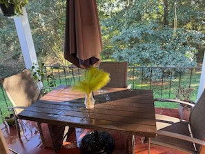 A wooden patio table with a vase of yellow flowers, a brown umbrella, and a chair. - Superb 3-bedroom house with AC in vibrant Atlanta (Atlanta)