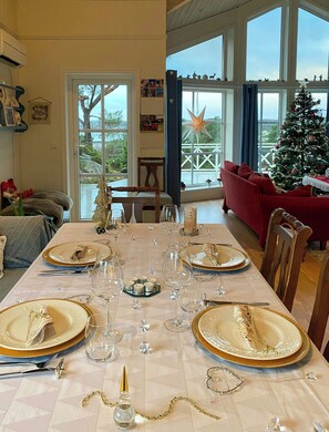 A dining area with a table set for four, large windows, a Christmas tree, and a view of the outdoors. - Cabin near Tveitafossen and Fitjarfjellet (Fitjar)