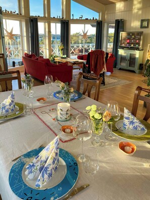 A dining area with a table set for two, featuring floral tablecloths, clear glassware, and a candle centerpiece. - Cabin near Tveitafossen and Fitjarfjellet (Fitjar)