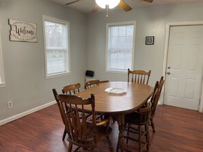 A dining room with a wooden table and chairs, a ceiling fan, and a 'Welcome' sign on the wall. - Spacious 7-bedroom house in serene Fort Wayne with AC. Big Groups only (Fort Wayne)