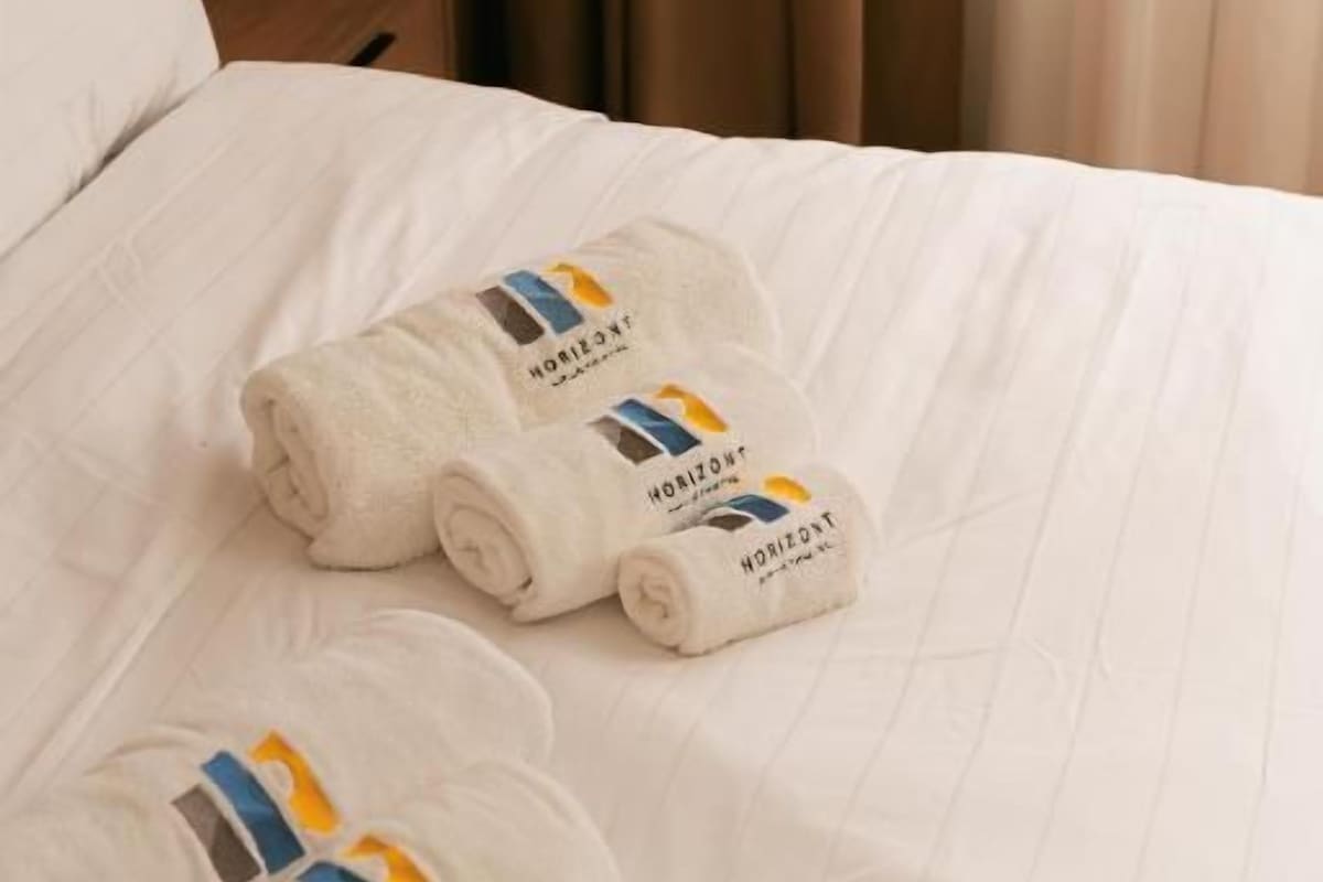 Ein Bett mit ordentlich gefalteten Handtüchern und einem Kissen.
