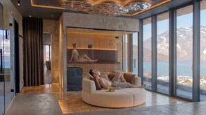 A modern interior with a large window, a circular seating area, and a view of a mountainous landscape. - Luxury Accommodation on 200m2 With Private spa (Beckenried)