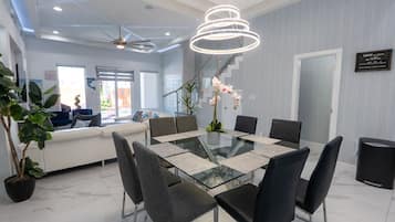A modern dining area with a glass table, black chairs, and a decorative orchid centerpiece.