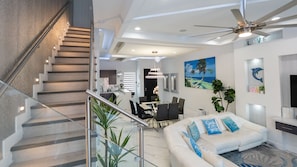 A modern interior with a staircase, dining area, and living space. - New 3br Townhome, Heated Pool, Beach Steps Spi 3 Bedroom Townhouse (South Padre Island)