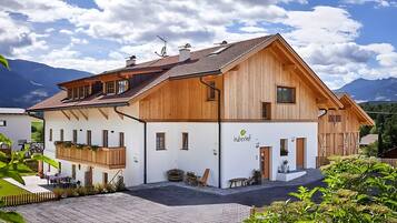 Ein zweistöckiges Holzhaus mit weißer Fassade und einem Balkon, mit einem Schild, auf dem 'huberhof' steht.