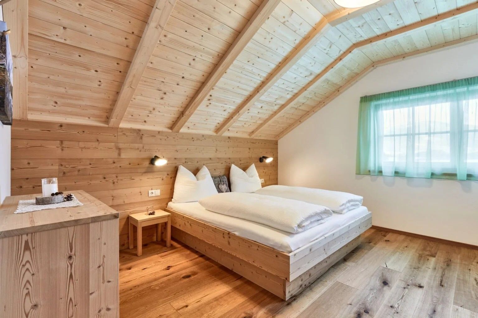 A wooden-paneled room with a bed, bedside tables, and a window with curtains.