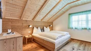 A wooden-paneled room with a bed, bedside tables, and a window with curtains.