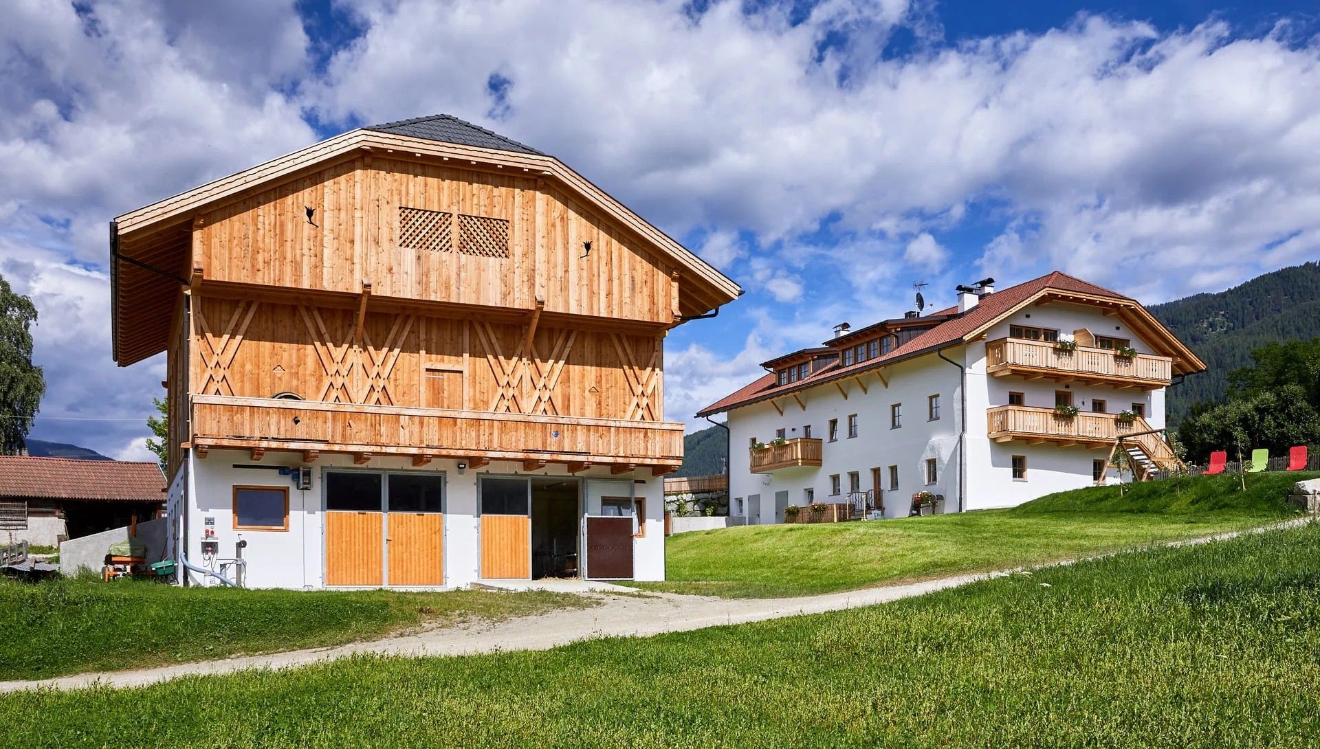 Eine Holzhütte mit Balkon und ein Gebäude mit rotem Dach in einer gebirgigen Gegend.