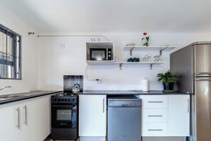 Eine moderne Küche mit Edelstahl-Kühlschrank, eingebauter Mikrowelle, Wasserkocher und Geschirrspüler.