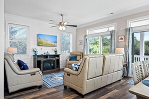 Ein Wohnzimmer mit Kamin, Ledersofas, Fernseher und Deckenventilator.